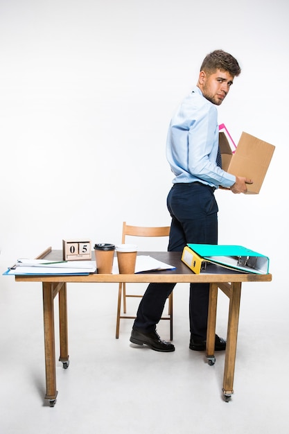 The young man is fired and folds things in the workplace, folders, documents. Couldn't cope with responsibilities. Concept of office worker's troubles, business, advertising, resignation problems.