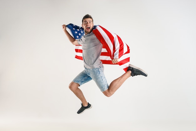 Young man jumping with flag of the United States of America isolated on white studio.