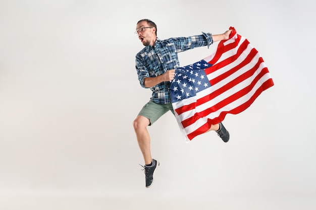 Young man jumping with flag of the United States of America isolated on white studio.