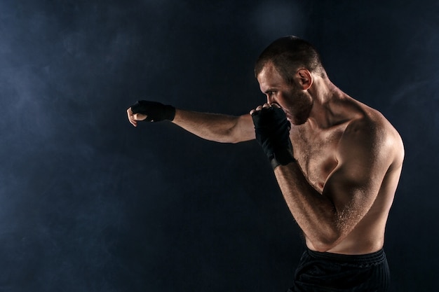 Free photo the young man kickboxing on black copyspace