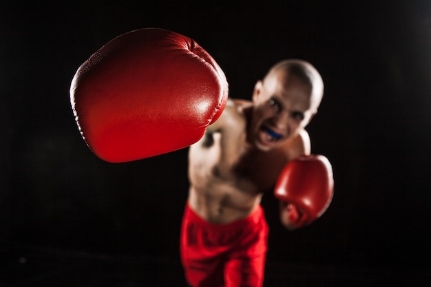 The young man kickboxing on black with kapa in mouth