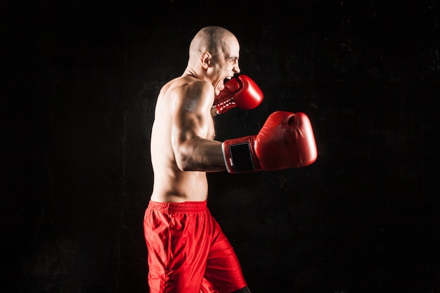 Free photo the young man kickboxing on black