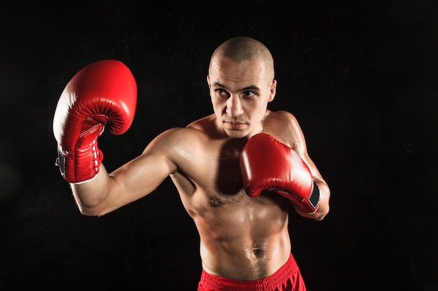 young man kickboxing on black