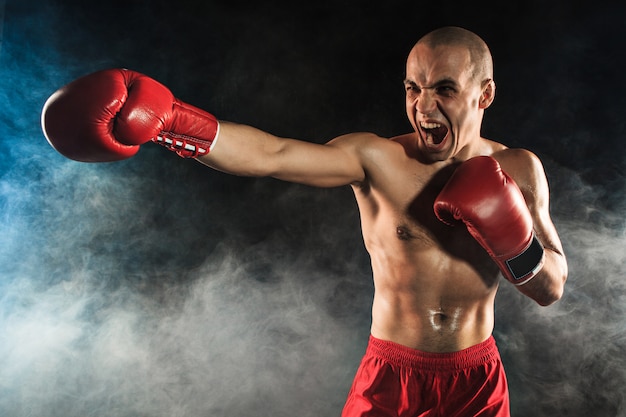 The young man kickboxing in blue smoke