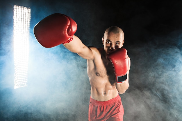 Young man kickboxing in blue smoke