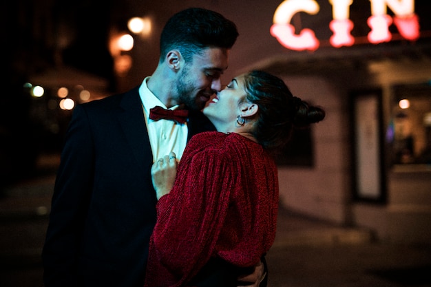 Young man kissing and hugging charming attractive happy woman on street