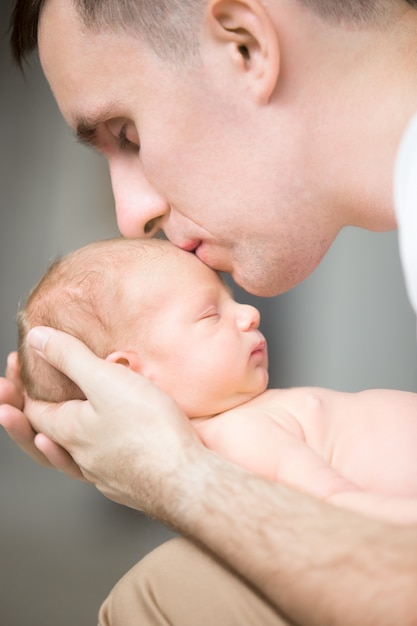 Free photo young man kissing a newborn in his palms