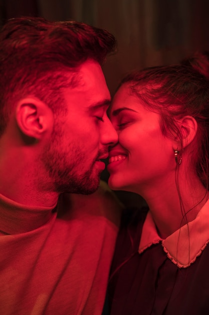 Young man kissing smiling woman in redness