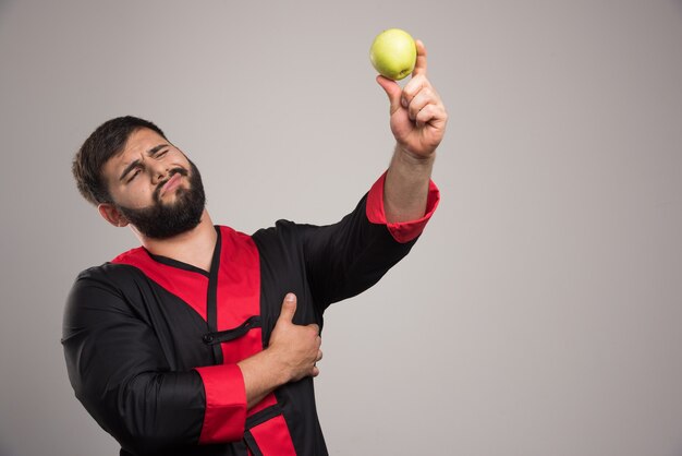 Young man looking on apple on dark wall .