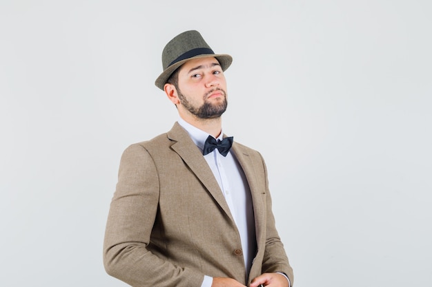 Young man looking at camera in suit, hat and looking confident , front view.