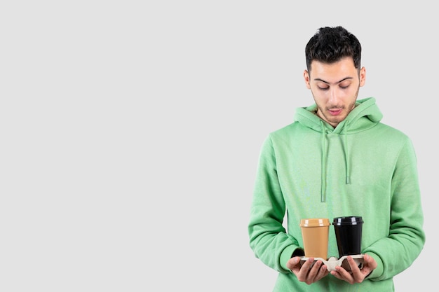 young man looking at coffee cups in his hands