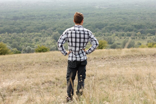 Young man looking down at forest full shot