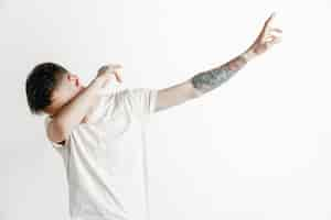 Free photo young man makes a dab movement with his arms on a gray background. human emotions, facial expression concept