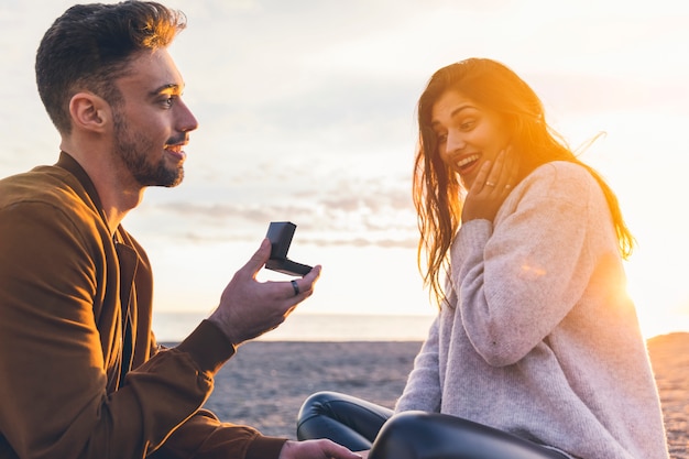 Young man making proposal to woman on sea shore