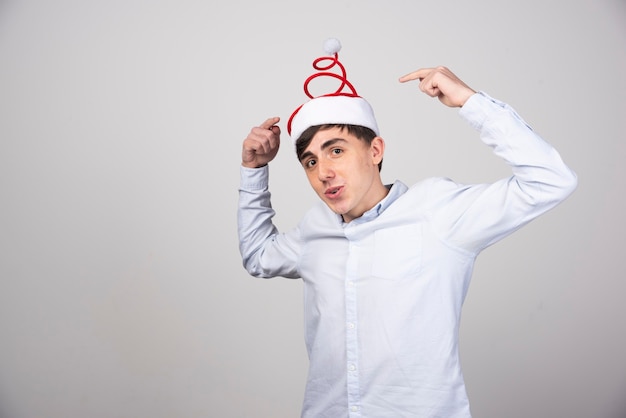 Free photo young man model standing and pointing at christmas hat