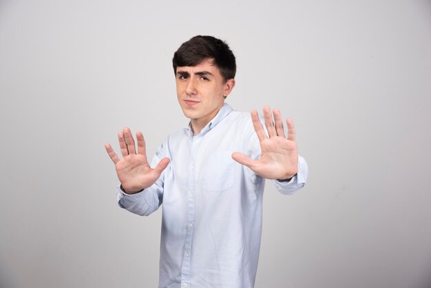 A young man model in white t-shirt standing and showing stop sign