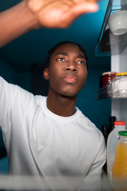 Young man opening the fridge at home for a snack in the middle of the night