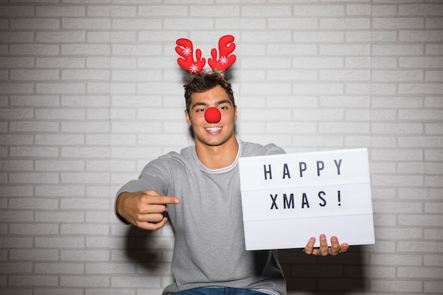 Free Photo young man in ornament deer antlers headband and nose with sign