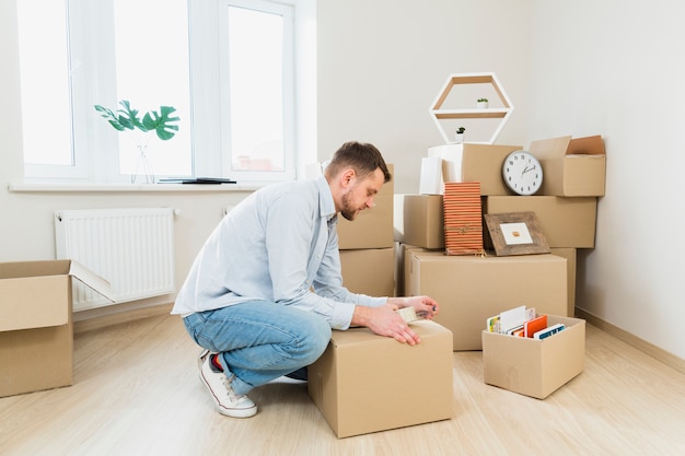 Free photo young man packing the cardboard boxes at home