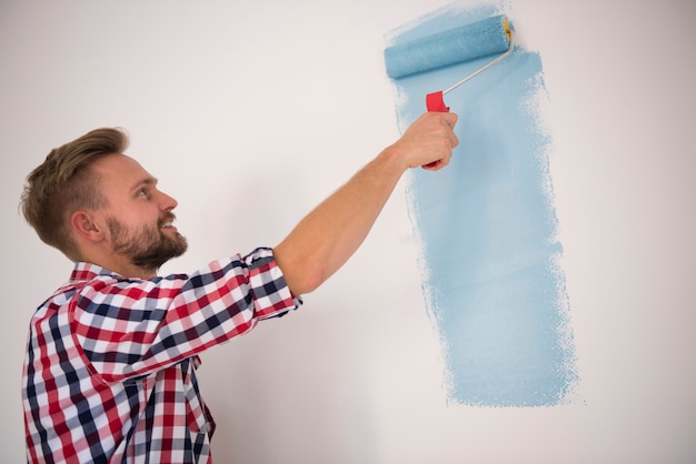 Young man painting a blue wall