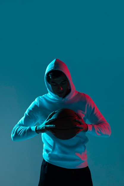 Young man playing basketball alone with cool lights