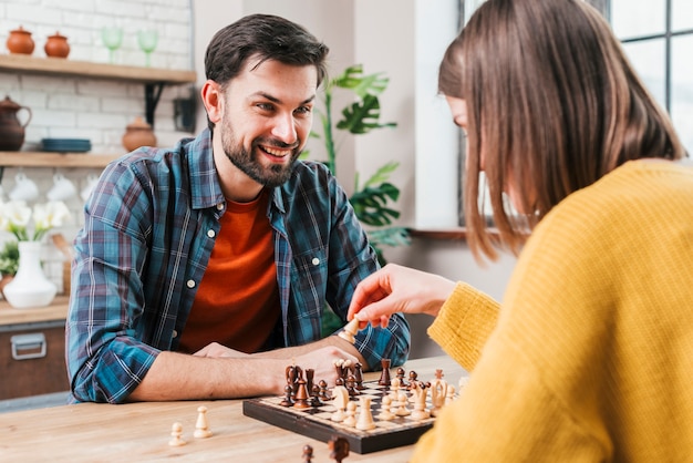 Free photo young man playing chess with his wife at home