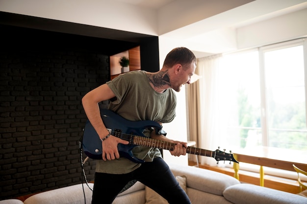 Free photo young man playing guitar at home