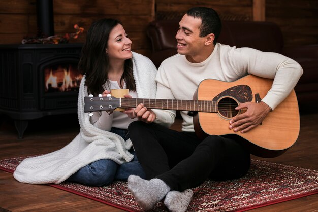 Young man playing guitar to woman