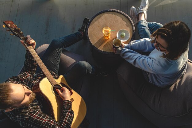 A young man plays the guitar for a girl top view