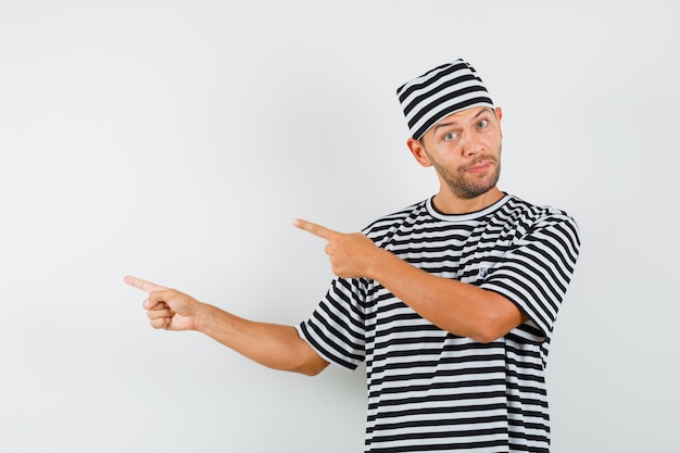 Young man pointing away and smiling in striped t-shirt hat  