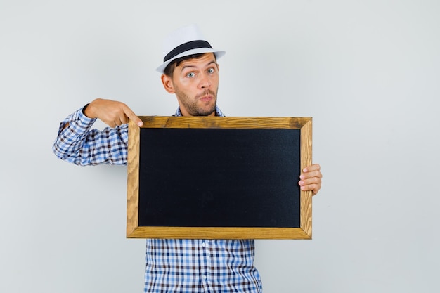 Free photo young man pointing at blackboard in checked shirt