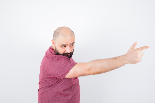 Young man pointing forward in pink t-shirt , front view.