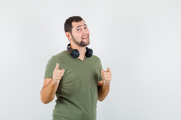 Young man pointing to the front in green t-shirt and looking cheerful