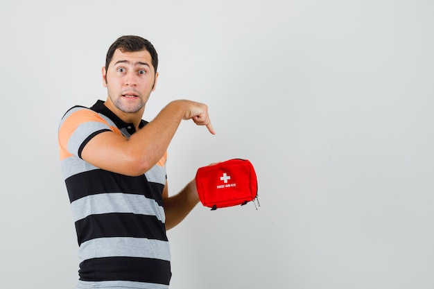 Free Photo young man pointing at inside of first aid kit in t-shirt and looking excited