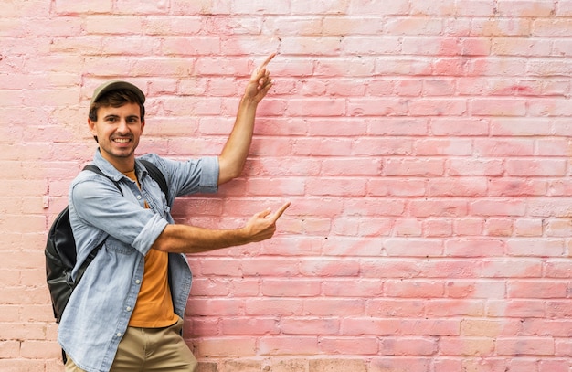 Free Photo young man pointing at pink wall