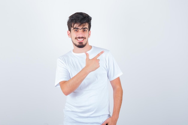 Young man pointing at upper right side in t-shirt and looking happy