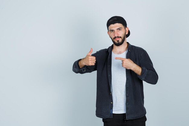 Young man pointing with finger and showing thumbs up