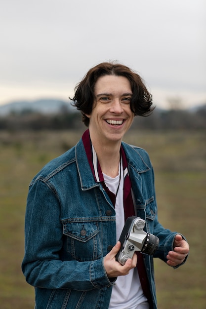 Free photo young man posing with camera in the field