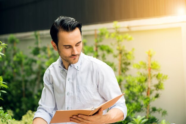 Young man reading a book in the park on a summer day.