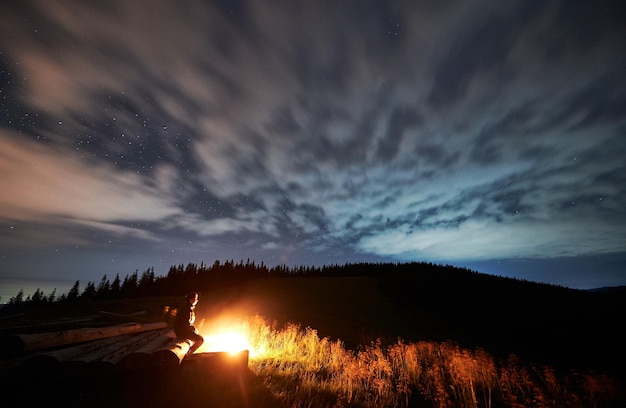 Free photo young man relaxing near bonfire in mountains