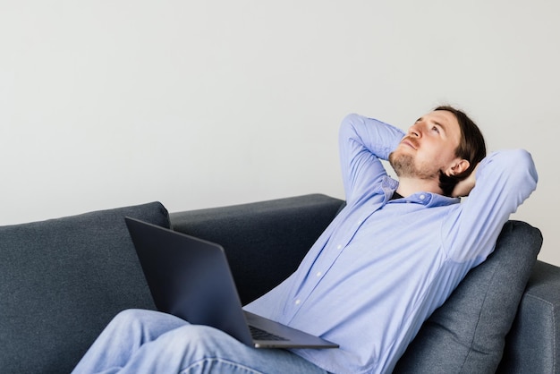 Young man resting on a couch with a laptop