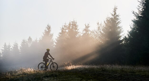 Young man riding bicycle in the mountains in early morning