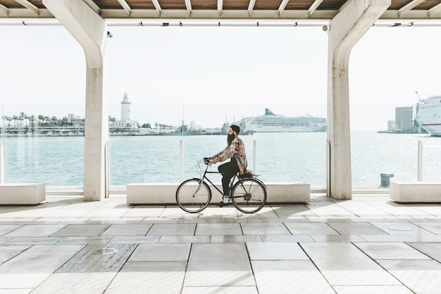 Free Photo young man riding the bicycle near the harbor