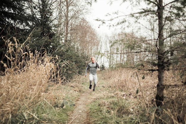 Free Photo a young man running on trail through forest