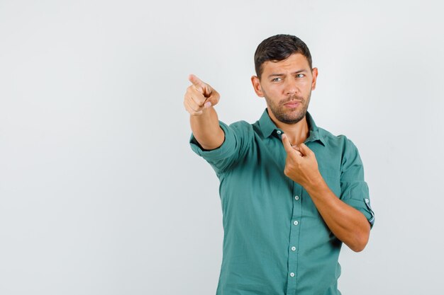 Young man in shirt showing something away and looking pensive