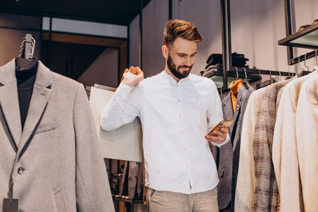 Young man shopping at menswear store and talking on the phone