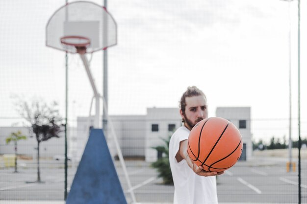 Young man showing basketball in court