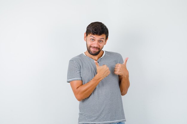 Young man showing double thumbs up in striped t-shirt and looking cheery , front view.