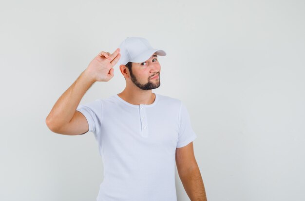 Free photo young man showing goodbye gesture in t-shirt and looking relaxed. front view.