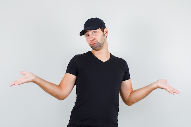 Young man showing helpless gesture in black t-shirt